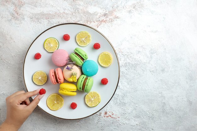 Top view french macarons delicious little cakes with lemon slices on a white space