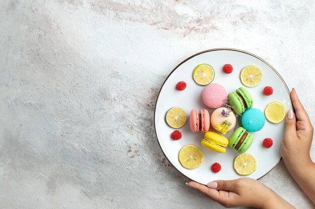 Top view french macarons delicious little cakes with lemon slices on white space