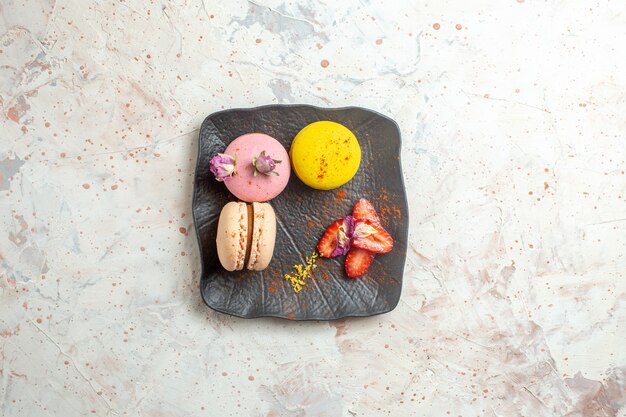 Top view french macarons inside plate on a white table biscuit cake sweet fruit