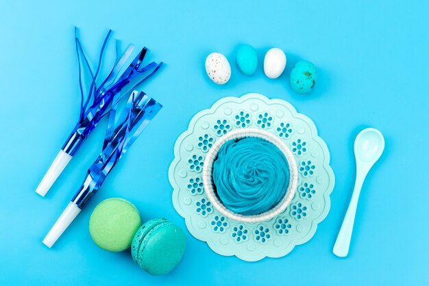 A top view french macarons with birthday whistles eggs on blue, cake biscuit confectionery