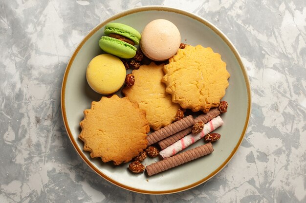 Top view french macarons with cakes and cookies on the white surface cookie biscuit sugar cake sweet pie