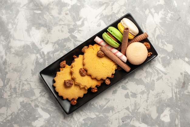 Top view french macarons with cakes and cookies on white surface cookie biscuit sugar cake sweet pie