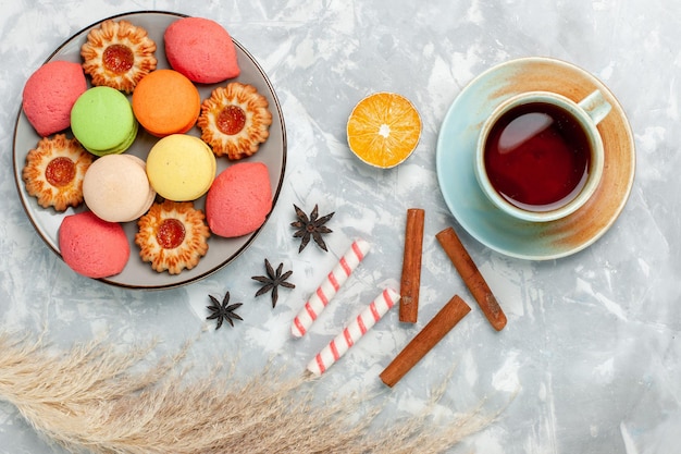 Top view french macarons with cookies and tea on light white surface