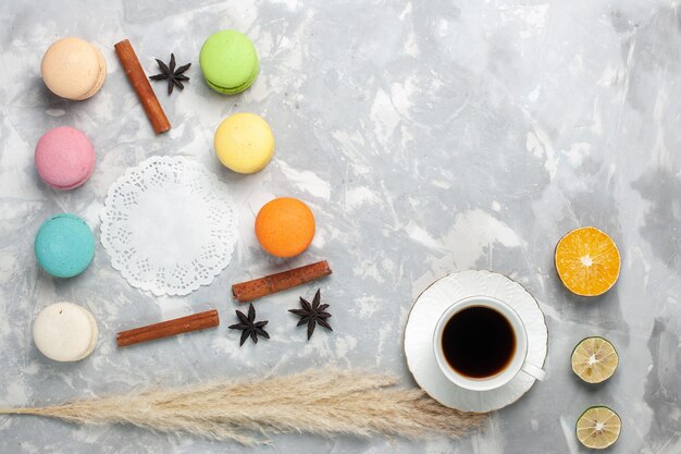 Top view french macarons with cup of tea on light white desk