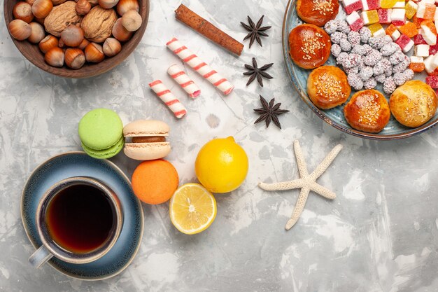 Top view french macarons with cup of tea on light white surface