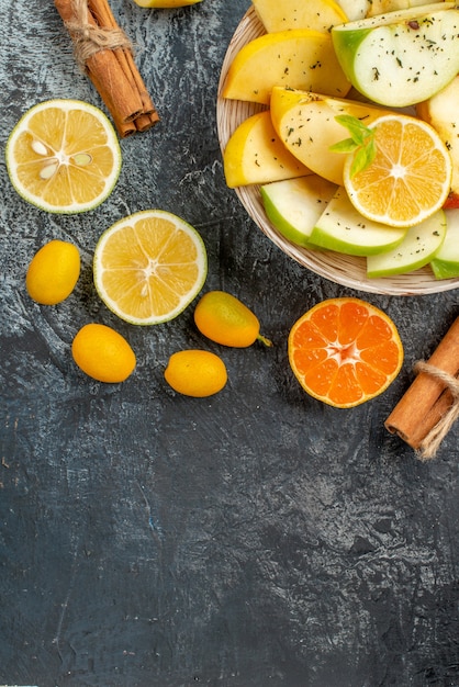 Vista dall'alto di fette di mela fresca su un piatto bianco con limone e cannella lime kumquat arance sul fondo sul tavolo grigio Foto Gratuite