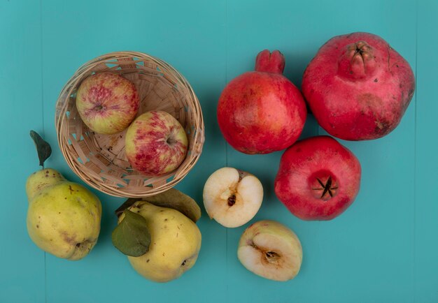 석류와 quinces 파란색 배경에 고립 된 양동이에 신선한 사과의 상위 뷰