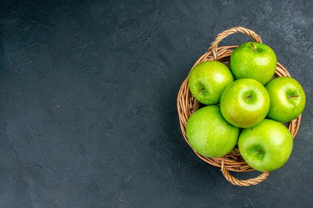 Top view fresh apples in wicker basket on dark surface free space