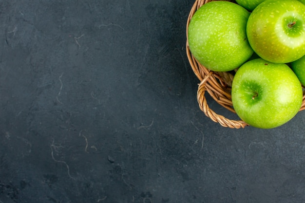 Top view fresh apples in wicker basket on dark surface with free space