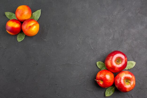 暗いテーブルの色の熟した果実に桃と新鮮なリンゴの上面図
