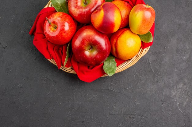 Вид сверху свежие яблоки с персиками внутри корзины на темном столе спелые свежие фрукты