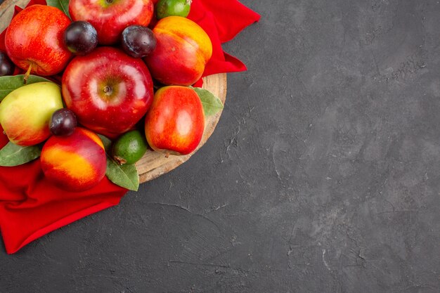 暗いテーブルの上の桃とプラムと新鮮なリンゴの上面図熟した果物の木まろやかなジュース