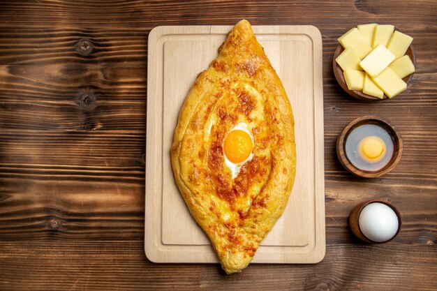 Top view fresh baked bread with cooked egg on brown wooden desk bread dough meal bun food breakfast eggs