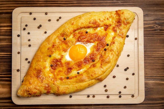 Top view fresh baked bread with cooked egg on brown wooden desk dough breakfast egg bun food