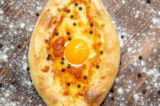 Free photo top view fresh baked bread with cooked egg and flour on a brown desk dough bake egg bread bun