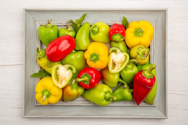 Top view fresh bell-peppers inside frame on a white table