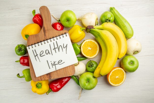 Top view fresh bell-peppers with bananas apples and orange on a white background salad healthy life photo ripe color diet