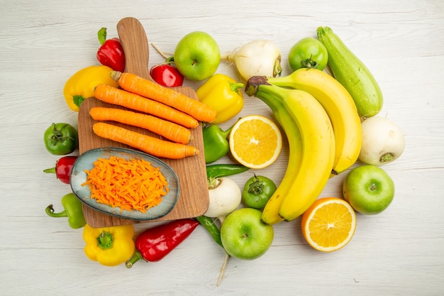 Вид сверху свежий сладкий перец с бананами, морковью и яблоками на белом фоне фото салат здоровый образ жизни спелый цвет диета