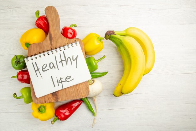 Top view fresh bell-peppers with bananas on white background diet salad healthy life ripe color