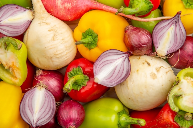 Top view fresh bell-peppers with radish and onions on a white table