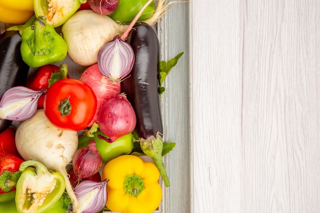 Top view fresh bell-peppers with radish and onions on white table