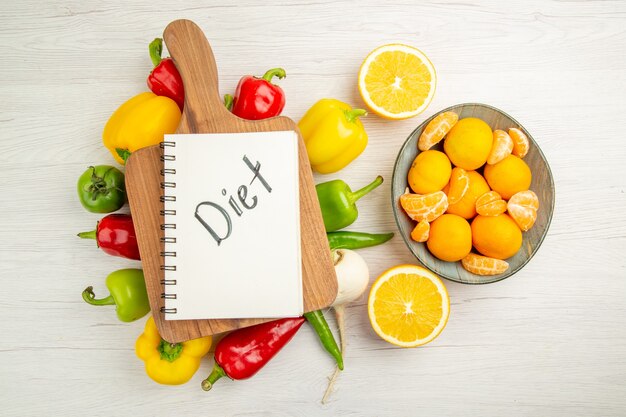 Top view fresh bell-peppers with tangerines on white background salad ripe color photo healthy life diet