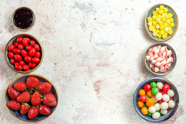 Top view fresh berries with candies on white table candy fruit berry