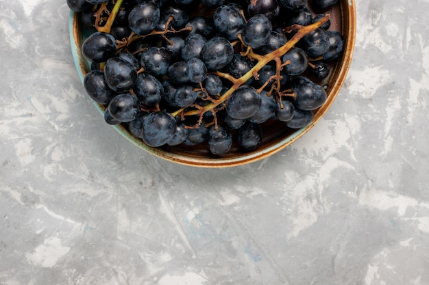 Вид сверху свежий черный виноград сочные спелые сладкие фрукты на светло-белом столе