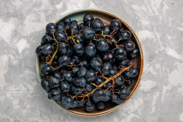 밝은 흰색 책상 위에 있는 신선한 검은 포도 즙이 많은 부드러운 달콤한 과일