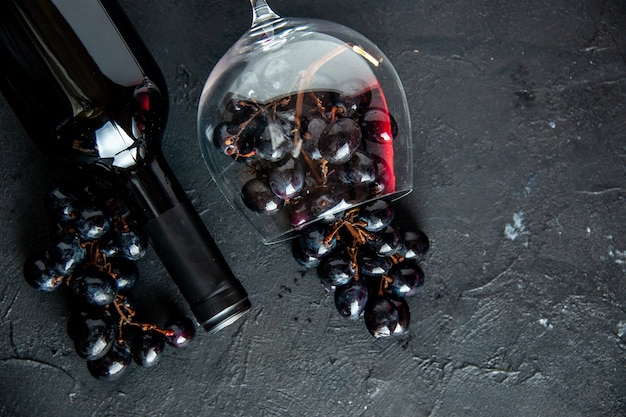 暗い背景の上のワイングラスワインボトルの上面図新鮮な黒ブドウ