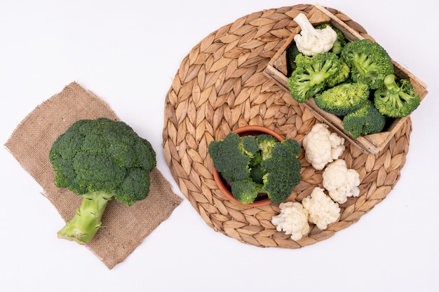 Top view fresh broccoli and cauliflower on sackcloth on white table