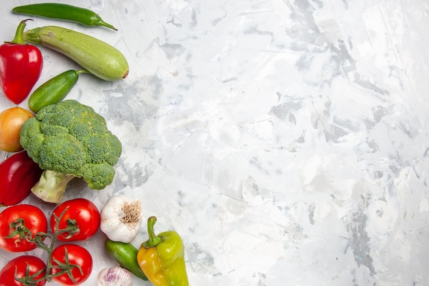 Вид сверху свежей брокколи с овощами на белом столе, диетический салат, спелое здоровье