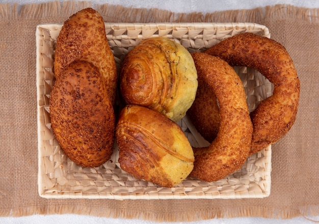 Top view of fresh buns on a bucket on a sack cloth on a white background