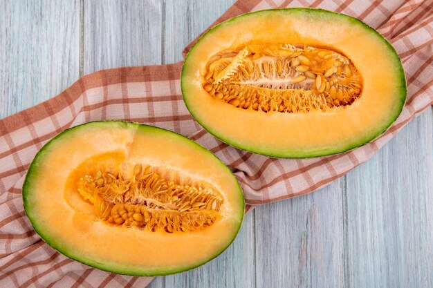 Top view of fresh cantaloupe melon on checked tablecloth on grey wood