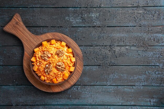 Top view fresh carrot salad grated salad with walnuts on dark desk color nut health diet salad