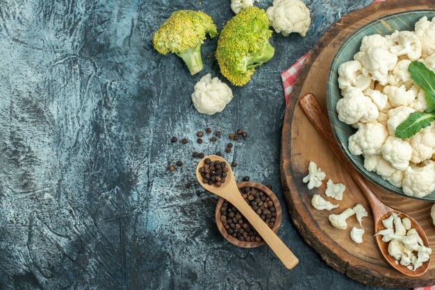 Top view fresh cauliflower with spoons and pepper on a light-grey table