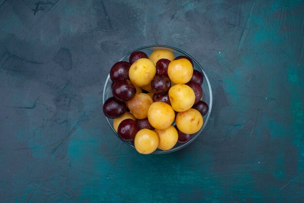 Вид сверху свежей вишни, спелых фруктов внутри стекла на темно-синем фоне, свежей вишни, спелой черешни