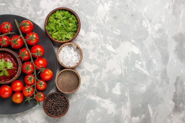 Free photo top view fresh cherry tomatoes inside plate with different seasonings on white surface