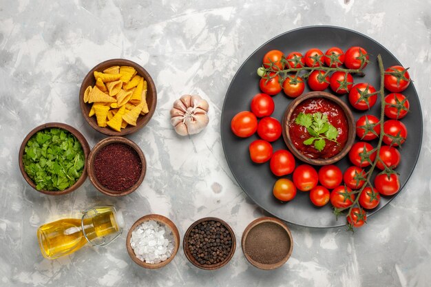 Top view fresh cherry tomatoes inside plate with seasonings on white surface