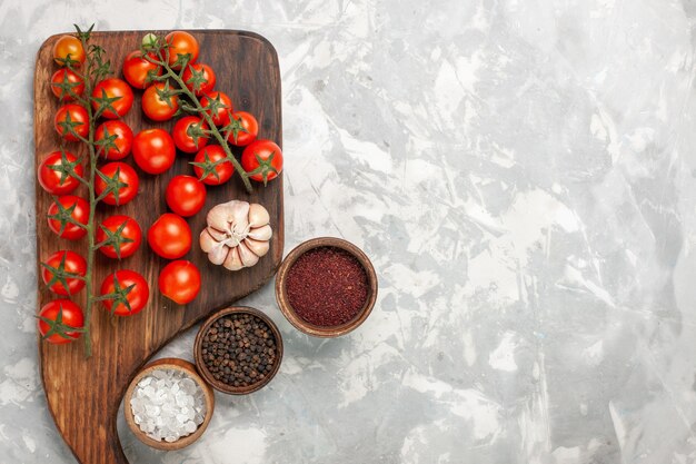 Top view fresh cherry tomatoes with different seasonings on light-white surface