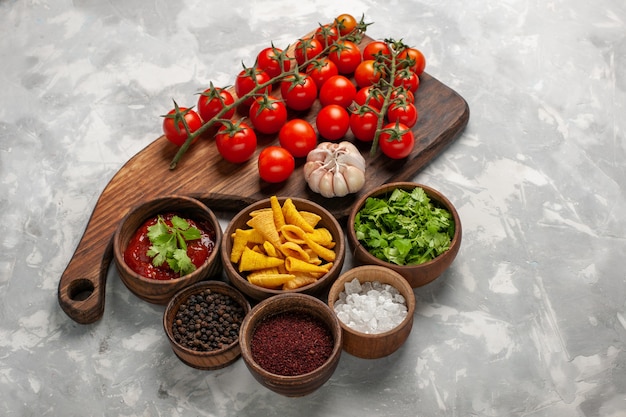 Top view fresh cherry tomatoes with different seasonings on white desk