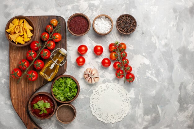 Top view fresh cherry tomatoes with seasonings and greens on white desk