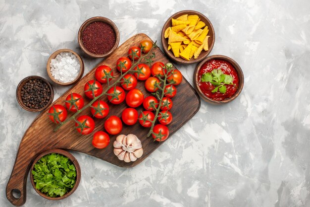 Top view fresh cherry tomatoes with seasonings and greens on white surface