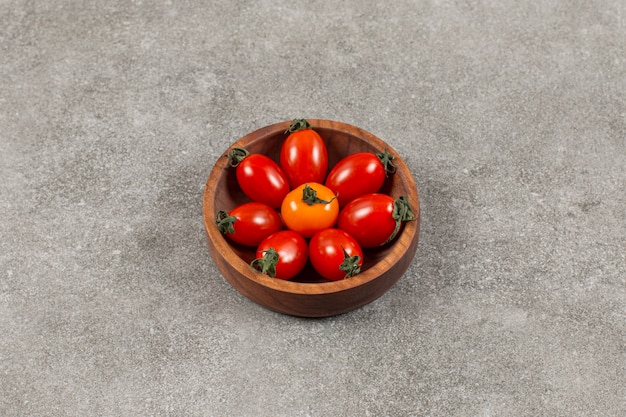 Top view of fresh cherry tomatoes in wooden bowl.