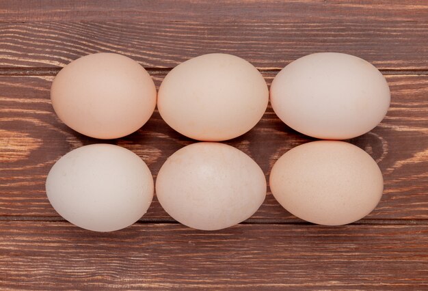 Top view of fresh chicken eggs arranged line on a wooden background