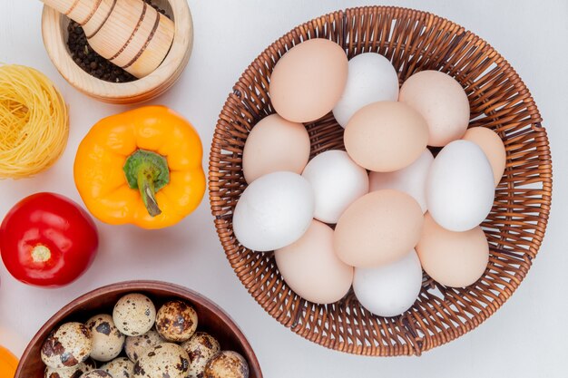 白い背景の上のトマトピーマンとバケツに新鮮な鶏の卵のトップビュー