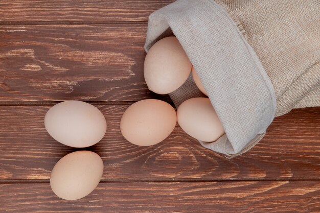 Top view of fresh chicken eggs on a burlap bag on a wooden background