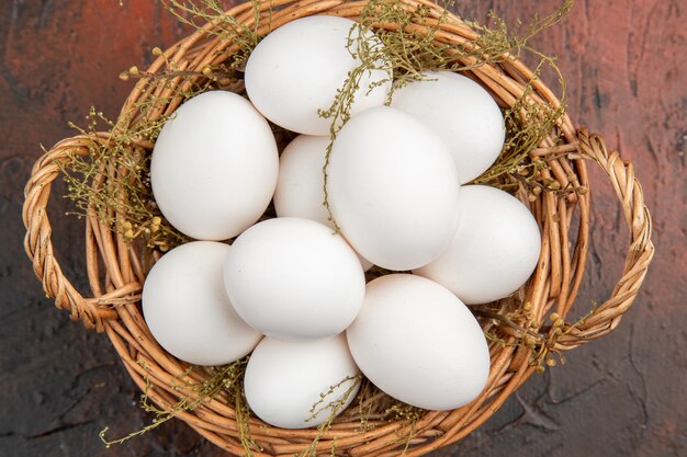 Top view fresh chicken eggs inside basket on a dark table