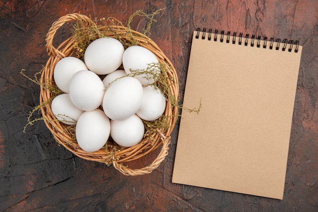 Free photo top view fresh chicken eggs inside basket on dark table