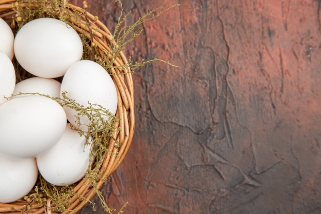 Top view fresh chicken eggs inside basket on dark table